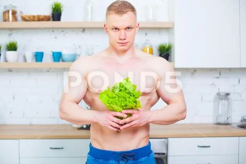 Muscular Man With A Naked Torso In The Kitchen With A Salad Concept Of