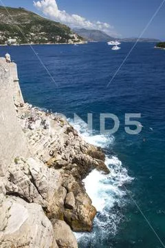 Cliff on the city wall of Dubrovnik with swimmers
