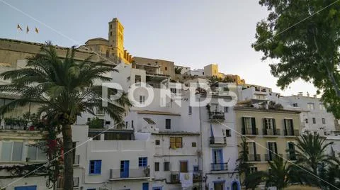 Facades of houses with fortress in Eivissa Ibiza town at sunset, Spain