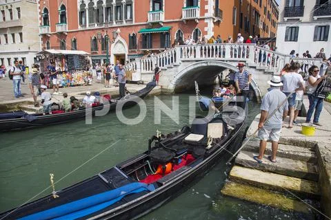 Tourists crowd at the quay and gondolas in Venice, Italy