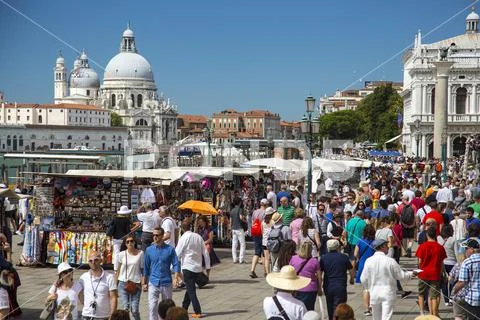 Crowds of tourists in the streets of Venice with Basilica di Santa Maria della Salute