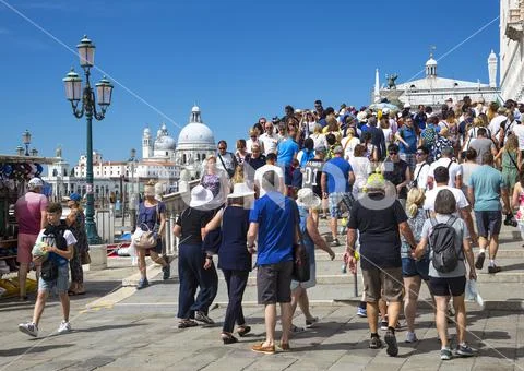 Crowds of tourists on the bridges of Venice with Basilica di Santa Maria della Salute