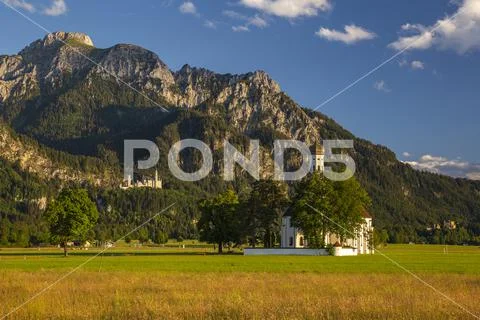 Alps in the evening light with Neuschwanstein Castle and Sankt Coloman Church