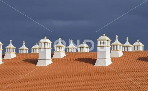Roof with chimneys against dark clouds