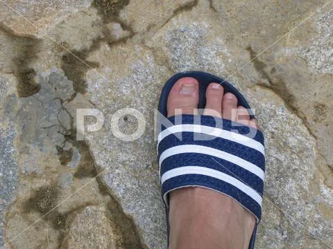 Right foot in flip-flops on stone floor