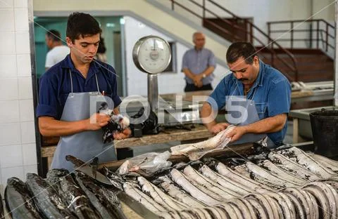 Fishmonger cutting up and selling fresh Black scabbard fish