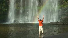 Man and tropical waterfall with rainbow