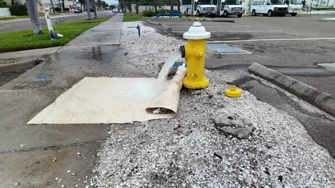 0002A bright yellow fire hydrant spews a steady stream of water into a gravel pa Видео 332723791