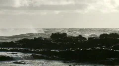 Large waves crashing over rocks in wall of spray
