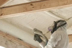 Technician spraying foam insulation into ceiling
