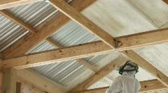 Technician spraying foam insulation into ceiling of a building