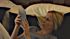 Woman reading Kindle tablet in bed