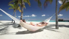 couple relaxing in hammock on tropical beach