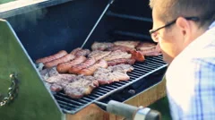 Handsome man grilling steak on the barbeque, steadicam shot