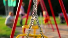 Unrecognizable children ride on the swings at the playground