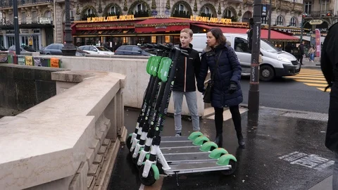 01 Rainy gray winter day Paris boy watch hire electro scooters for rent on a  Stock Footage 100814998