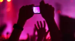 Hands hold camera with digital display among people at rave party