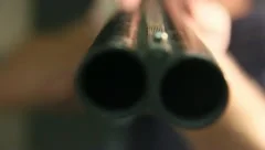 Loading and pointing a double barreled shotgun at the camera 