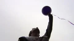 Slow mo of teen releasing balloon into the sky