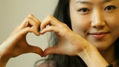 Beautiful young Asian woman makeing heart gesture with hands