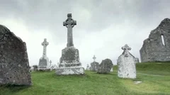 Christian Celtic Cross grave Crosses in Graveyard in Ireland pan to old Church