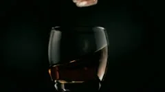 Ice cube falling in super slow motion in whiskey