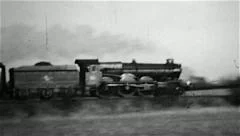 Steam railway locomotive engine on a passenger train in an old B&W film