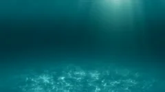 Underwater scene of ocean floor with light rays from surface and floating algae