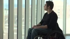 Man in wheelchair looking out a highrise window