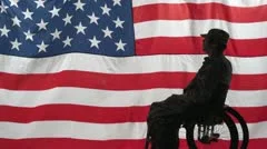 Silhouette of a soldier in a wheelchair in front of US flag