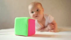 Cute smiling baby crawling to a toy cube for the camera