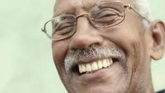 Old black man with glasses and mustache smiling