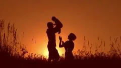 Happy family: father, mother and baby playing at sunset. Silhouettes