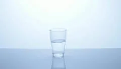 hand puts half full glass of water on the table, middle