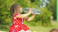 Adorable girl in beautiful dress drink water from large bottle