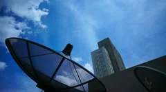 Black antenna communication satellite dish over sky in cityscape - time-lapse