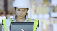 Female warehouse employee is working on a digital tablet and checking inventory