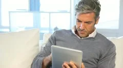 man sitting in sofa at home with electronic tablet