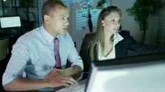 Businessman and businesswoman working late at night in a room full of computers