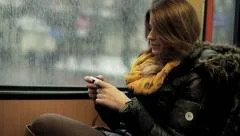 Young woman using smartphone while riding tram, steadicam shot HD