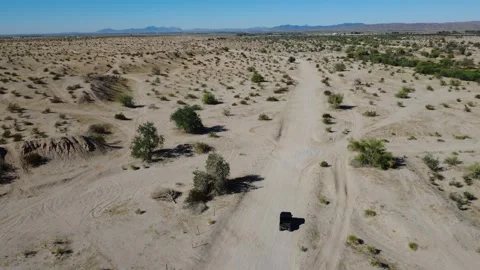 02 Desert Aerial Fly Over Off Roading Vehicle in sandy terrain and Green Shrubs Stock Footage 323774099