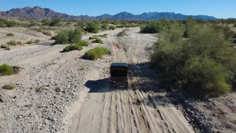 02 Desert Aerial Tracking Off Roading Vehicle through sandy terrain Green Trees Stock Footage 323774097