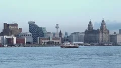 mersey ferry crosses in front of liverpool skyline at dusk