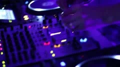Hands of DJ tweak controls on record deck in night club. Turntable, mixer, plate