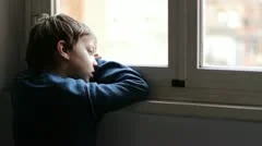 child sad and alone looking through window