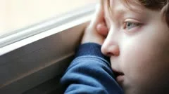 beautiful child bored and sad looking through window
