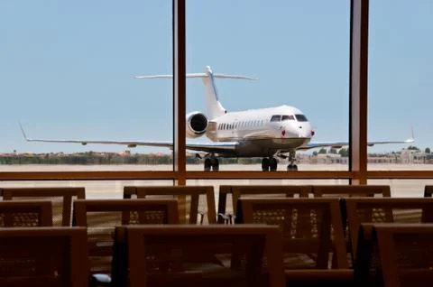 business  plane  parked  in  an  airport  with  seats  on  foreground.  focus  on  the  plane. xkwx seat,  metal,  plane,  angled,  mode,  travel,  business,  jet,  private,  vehicle,  transport,  airplane,  blue,  airport,  air,  white,  corporate,  contemporary,  asphalt,  commercial,  luxury,  class,  stationary,  transportation,  sky,  upper,  space,  nobody,  horizontal,  star,  wealth,  charter,  parked,  business,  technology,  challenger,  object,  front,  sparse,  single,  road,  chassis,  wing
