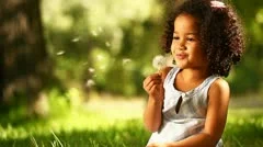 little girl blowing dandelion seeds in the park