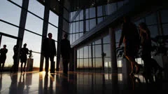 Business people walking through a modern office building at sunset