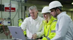 3 workers in a warehouse with a laptop are discussing their work.